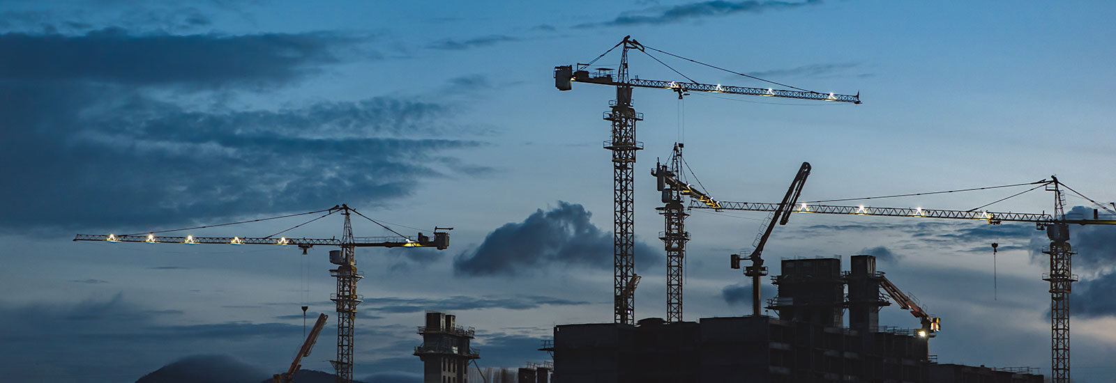 Grúas en un sitio de construcción al atardecer.